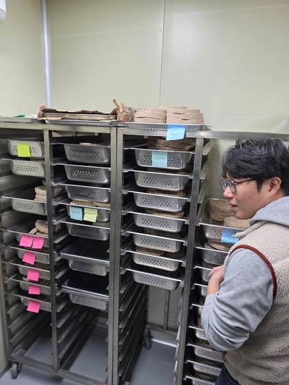 Bock inspecting nuruk drying racks at Baekkyung Distillery