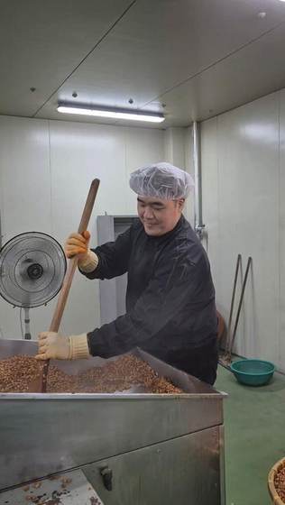Hand-turning fermenting soybeans at Jukjangyeon